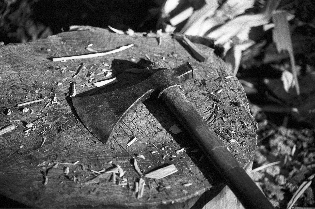 A hand holding an axe next to a drink, tools laid out